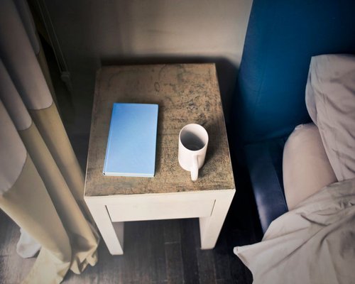 A cup of water and a book on a bedside table showing a resting environment
